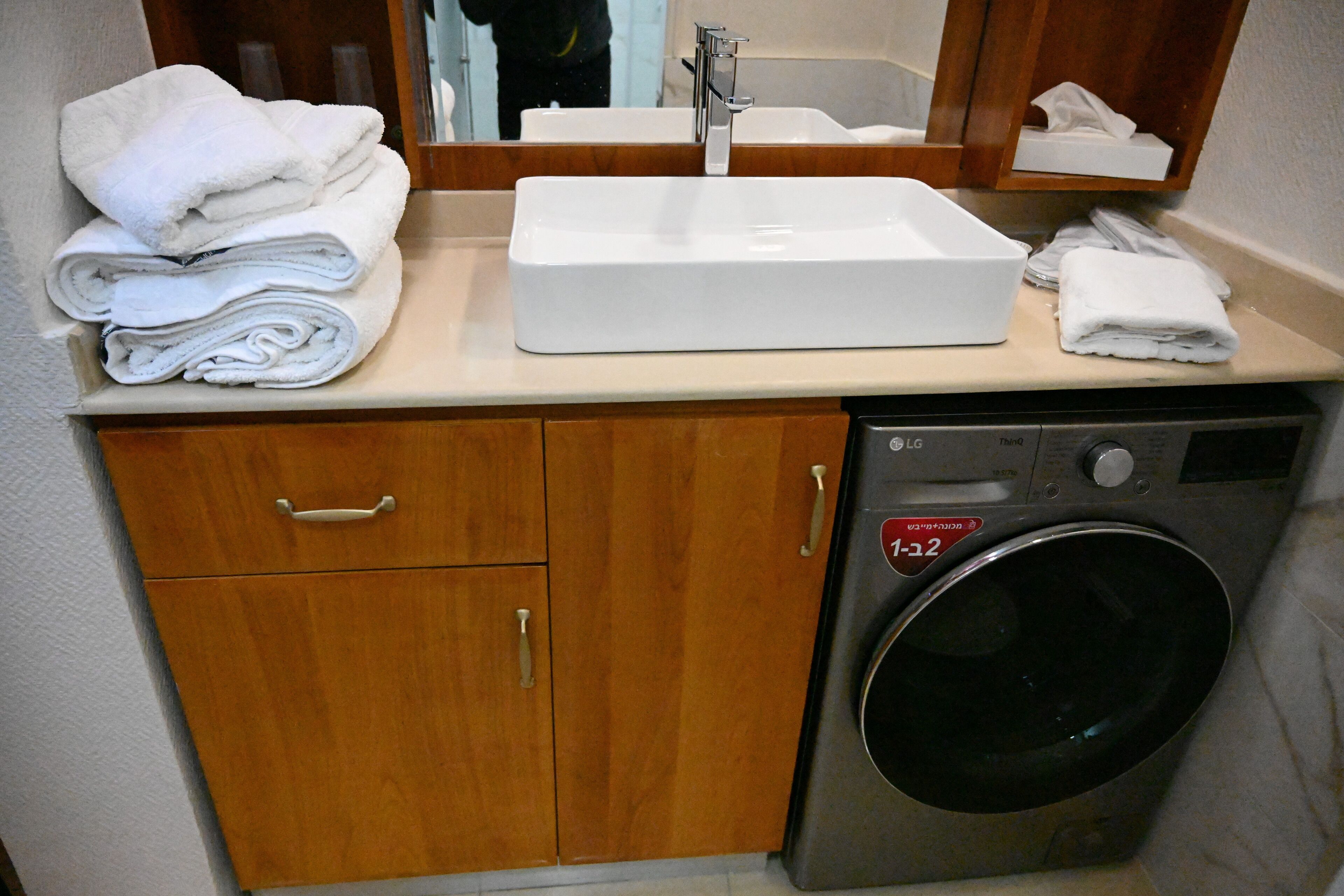 Une petite salle de bain d’hôtel comprenant un lavabo, un miroir et un lave-linge.