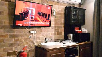 Une cuisine équipée d’un téléviseur fixé au mur, d’un extincteur et d’une machine à café.