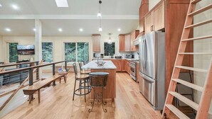 A spacious kitchen with wooden cabinets, a stainless steel refrigerator, and a large island with bar stools.