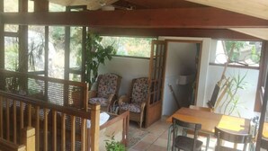 Un patio cubierto con mobiliario de madera, incluyendo una mesa y sillas, y una planta en maceta.