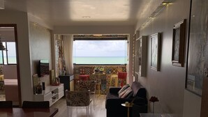 A spacious living area with a balcony, a dining table, and a sofa. - Paraíso Frente mar (Maceió)