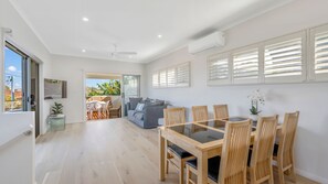 A modern interior with a dining area, a sofa, and a view to an outdoor patio.