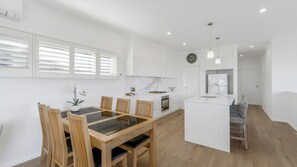 A modern kitchen with white cabinetry, a central island with a sink, and a dining area with a wooden table and chairs.