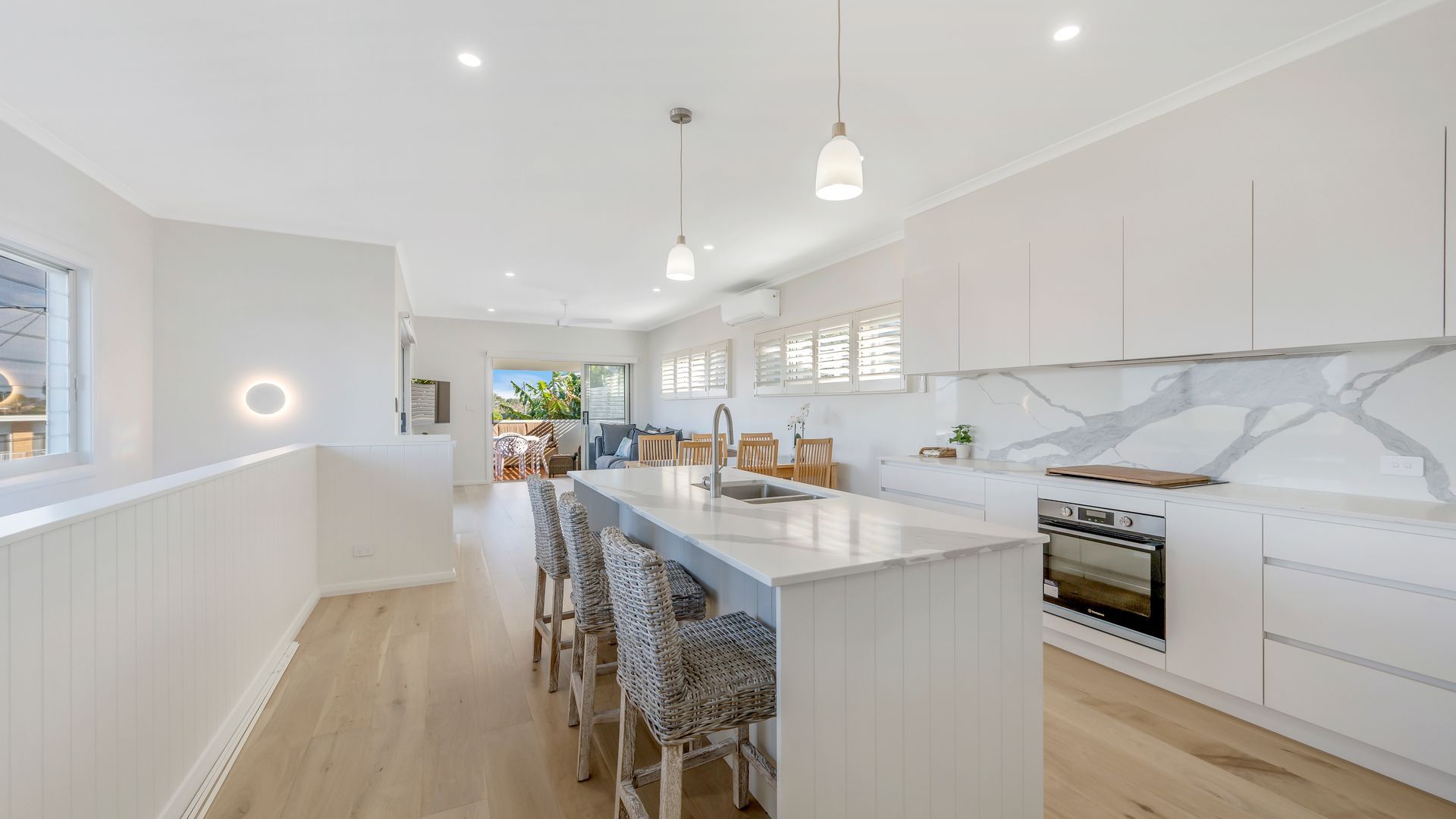 A modern kitchen with a central island, white cabinetry, and a marble backsplash.