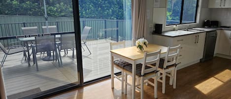 Eine moderne Küche mit Essbereich, großen Fenstern und Blick auf Grünflächen.