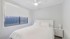 A bedroom with a bed, a nightstand, a lamp, and a ceiling fan. - Coastal Charm - Tastefully furnished holiday house (Port Macquarie)