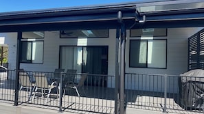 A modern building with a covered outdoor seating area, large windows, and a metal fence. - Coastal Charm - Tastefully furnished holiday house (Port Macquarie)