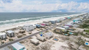 Una zona residenziale sulla costa, con spiaggia, case e una strada.