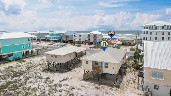 Une zone côtière avec de nombreuses maisons situées en bord de mer, dont certaines sont surélevées sur pilotis, et qui offre une vue dégagée sur l’océan.
