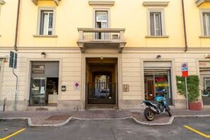 A building with a yellow facade, a motorcycle parked in front, and a sign indicating a no parking zone. - Modern Apartment in Via Carloni by Wonderful Italy (Como)