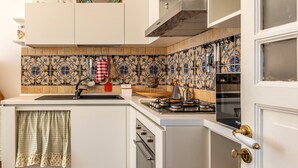 Une cuisine avec un plan de travail recouvert de carreaux, une cuisinière à gaz et un évier.