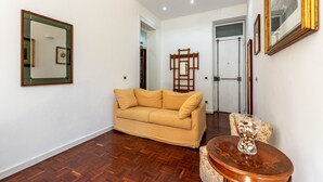 Un salon avec un canapé beige, une table basse ronde en bois et un miroir au mur.