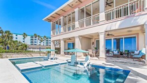 A pool area with lounge chairs, a covered seating area, and a two-story building with balconies. - Ocean Dream Villa | Beachfront Indian Rocks Beach (Indian Rocks Beach)
