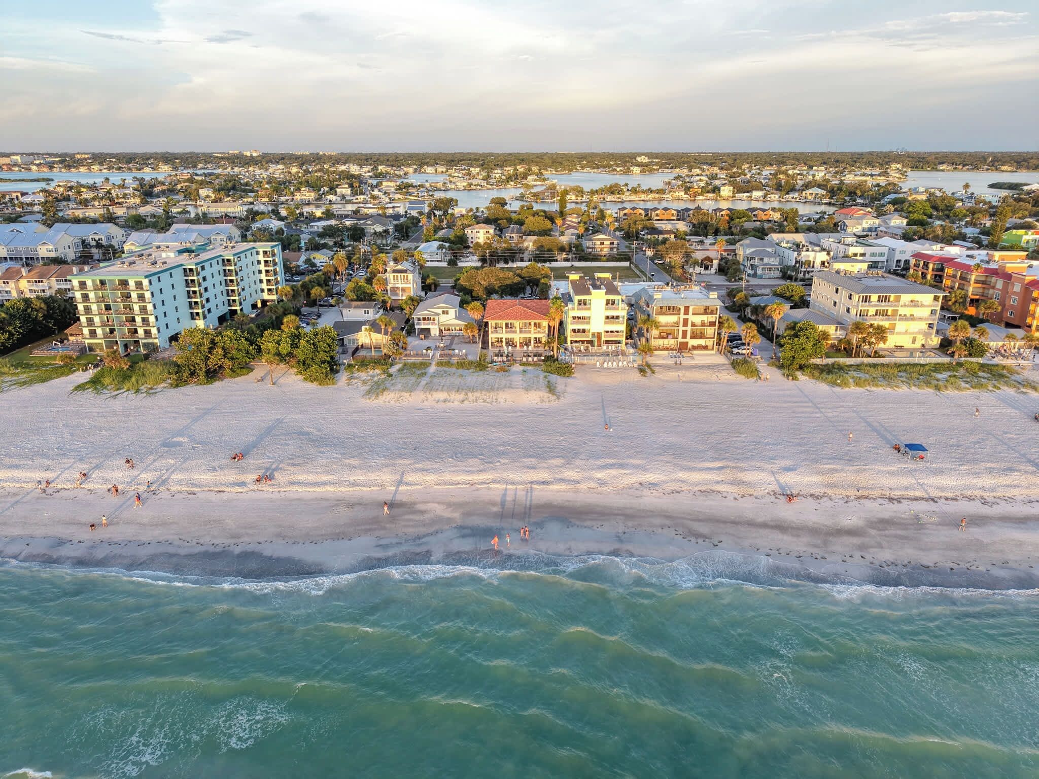 En kuststad med bostäder som ligger direkt vid stranden, en sandstrand och utsikt över havet.