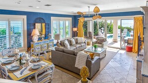 A spacious living area with a sofa, dining table set for four, and a view of the outdoors. - Ocean Dream Villa | Beachfront Indian Rocks Beach (Indian Rocks Beach)