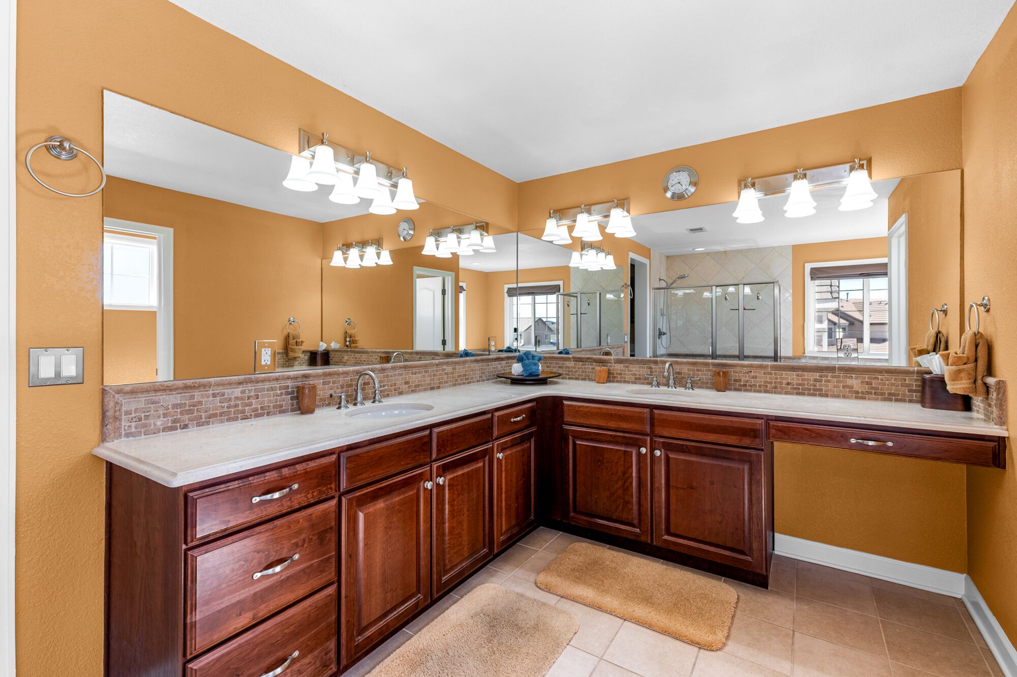 A spacious bathroom with a large vanity, multiple mirrors, and modern lighting fixtures.