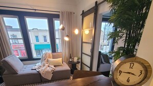Un salon chaleureux avec un canapé, une table en bois, une horloge et une boîte étiquetée « Miller’s Baker ».