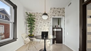 Une pièce moderne avec une table ronde, une chaise, une plante en pot et une bibliothèque.