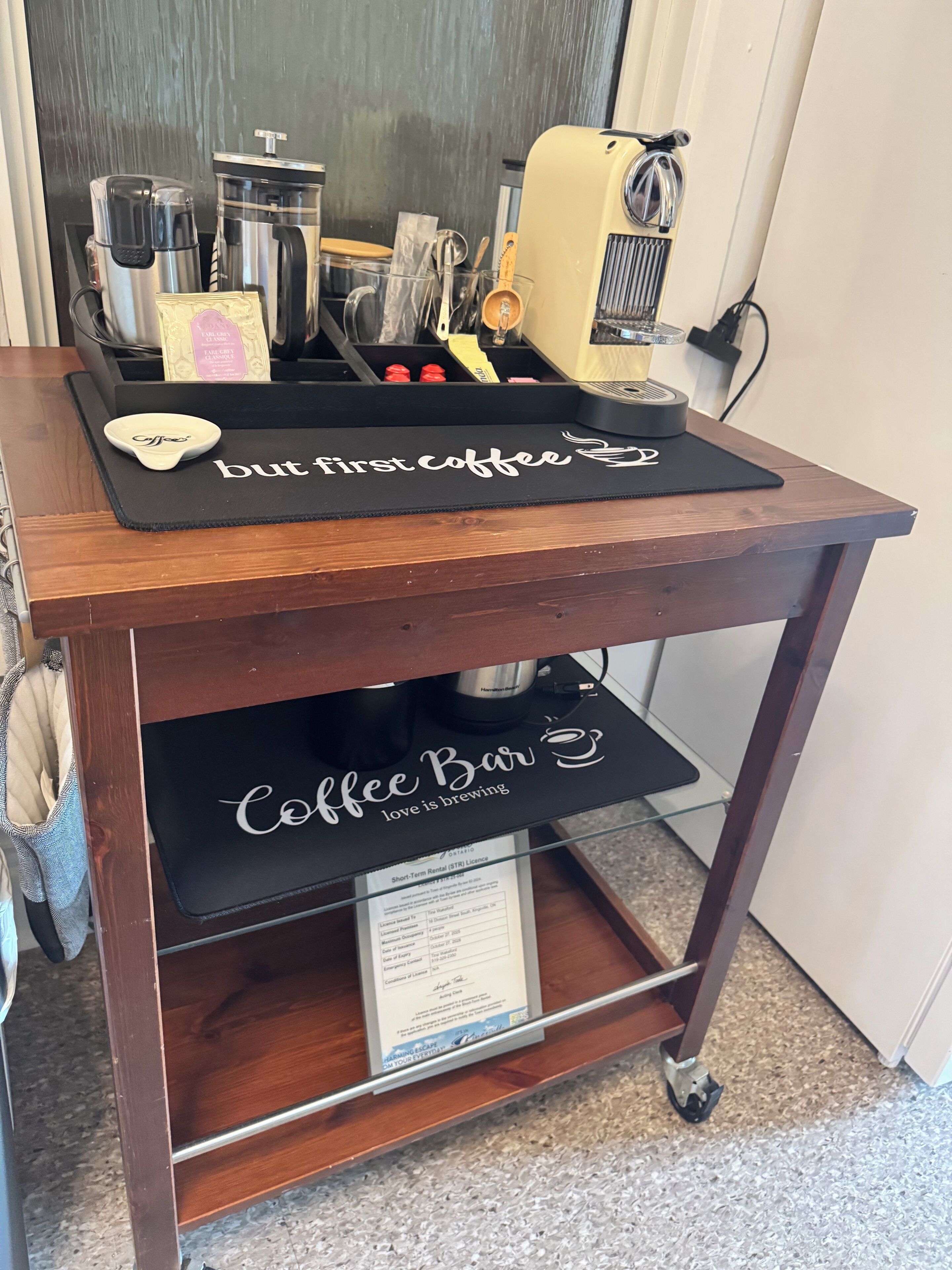 A coffee cart with a 'but first coffee' mat, a coffee machine, and a 'Coffee Bar' sign.