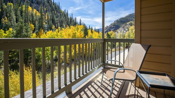 A wooden deck with a view of a forested mountain range and autumn foliage. - Woodbridge Inn Retreat: Perfect Frisco Location (Frisco)