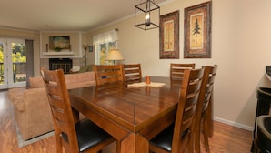 A dining area with a wooden table and chairs, a hanging light fixture, and two framed pictures on the wall. - Woodbridge Inn Retreat: Perfect Frisco Location (Frisco)