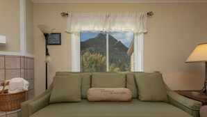A green sofa with a cushion that reads "Home is wherever I'm with you." A wicker basket with towels is on the floor beside the sofa. - Woodbridge Inn Retreat: Perfect Frisco Location (Frisco)