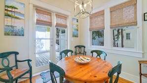 A dining area with a wooden table, six chairs, a chandelier, and artwork on the walls. - Large 1BD  Stand Alone Home in Seaside w/Tower & Porches + 2 Adult Bikes! (Santa Rosa Beach Fl)