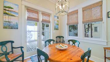 A dining area with a wooden table, six chairs, a chandelier, and artwork on the walls.