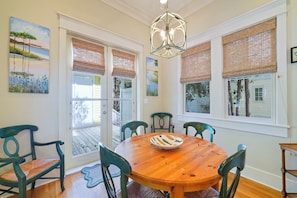 A dining area with a wooden table, six chairs, a chandelier, and artwork on the walls. - Large 1BD  Stand Alone Home in Seaside w/Tower & Porches + 2 Adult Bikes! (Santa Rosa Beach Fl)