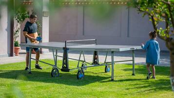 A portable ping pong table on a grassy area with a building in the background.
