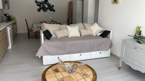 Un dormitorio moderno con una cama grande, un comedor y una cocina al fondo.