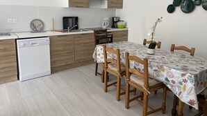 Una cocina moderna con armarios de madera, lavavajillas y un comedor con mesa y sillas.