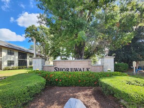 A sign reading "Shorewalk" surrounded by well-maintained hedges and a stone pathway.
