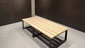 A room with a wooden bench, dark lockers, and a light-colored floor.