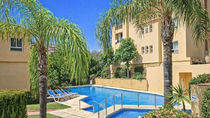 Una piscina rodeada de palmeras y un edificio con balcones.