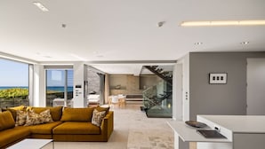 Una sala de estar moderna con un sofá, una mesa de centro y vista al océano.