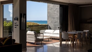 Un interior moderno con un gran ventanal corredero que da a un balcón con vistas al mar.
