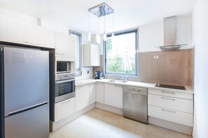 A modern kitchen with stainless steel appliances, white cabinetry, and a window providing natural light.