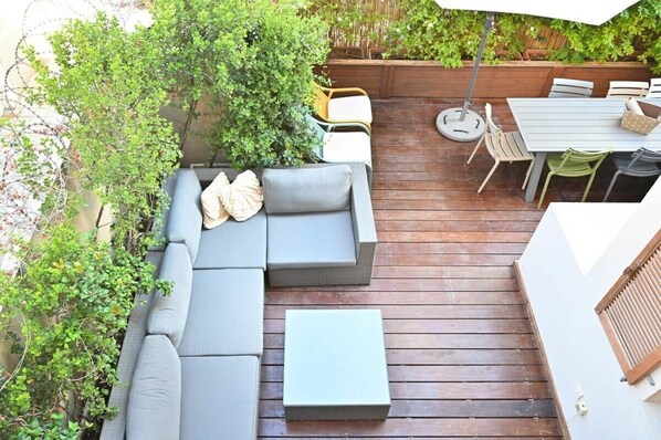 An outdoor patio with a sectional sofa, a small table, and a dining area with chairs.