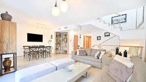 Una sala moderna con sofá, mesa de centro, televisor y comedor.