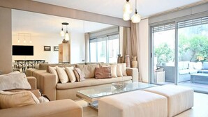 Una sala de estar moderna con un sofá, un reposapiés y una mesa de centro de vidrio.