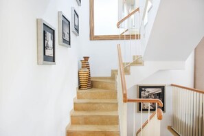A staircase with a wooden handrail, beige steps, and framed pictures on the walls.