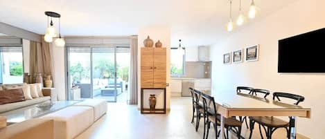 Una sala de estar moderna con sofá, mesa de comedor y sillas, un área de cocina y un gran ventanal con vistas.