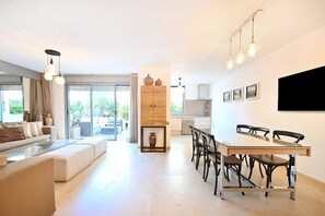 A modern living room with a sofa, coffee table, and dining area with chairs and a table.
