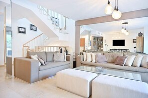 A modern living room with two sofas, a glass coffee table, and a staircase.