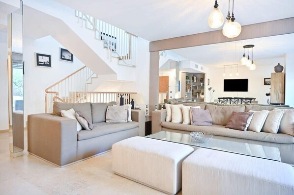 A modern living room with a sofa, ottoman, and a glass coffee table.