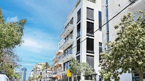 A multi-story building with balconies, a clear sky, and parked cars on the street. - Sweet Home 3BR near the sea by HolyGuest (Tel Aviv-Yafo)