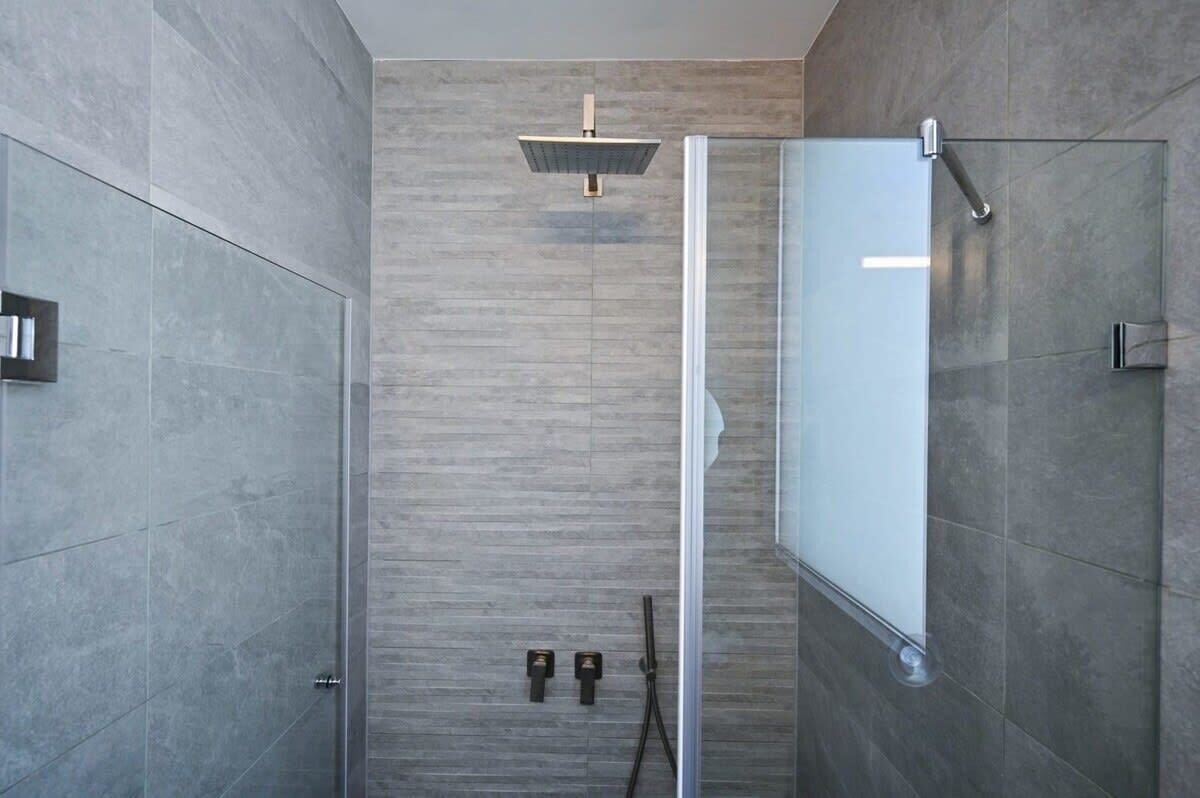A modern shower with a glass enclosure and a wall-mounted control panel.