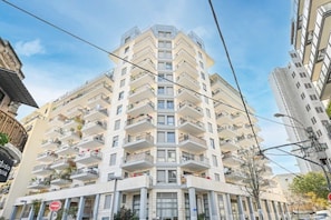 Un edificio residencial de varios pisos con balcones, un cartel que dice