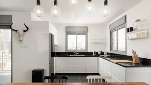 A modern kitchen with white cabinets, a black countertop, and a wooden dining table.